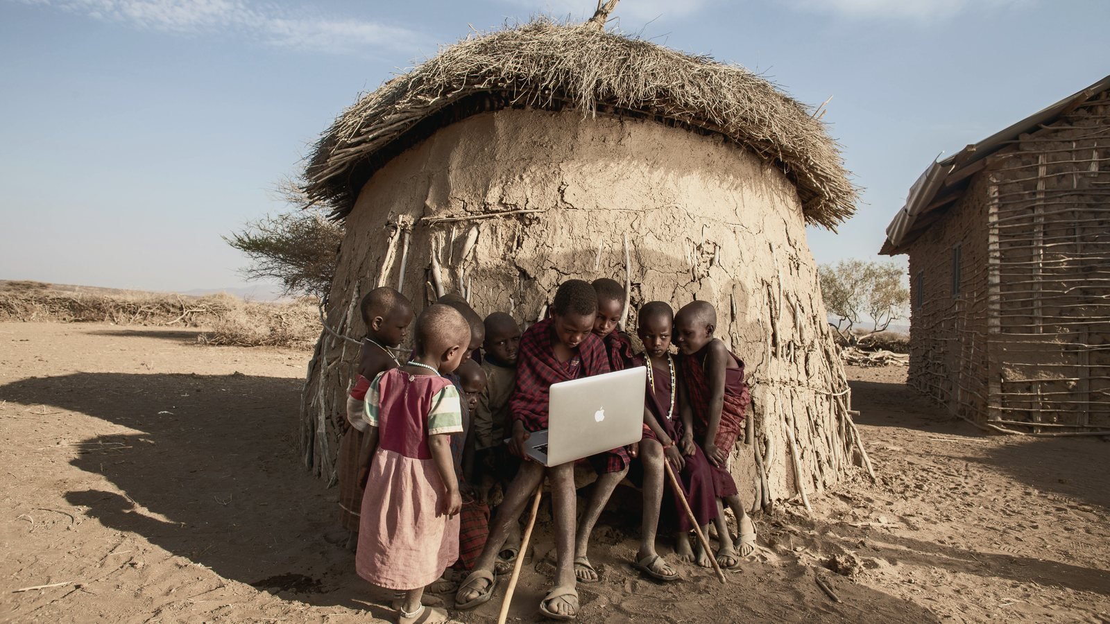 Un écran allumé devant un habitat traditionnel, en zone rurale.